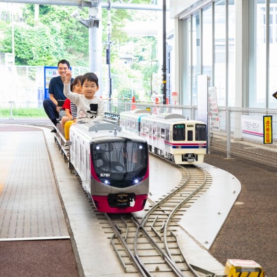 京王れーるランドのミニ電車に乗って笑顔の親子