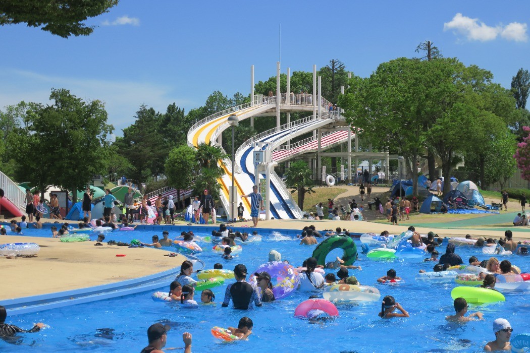 しらこばと水上公園の大型ウォータースライダーと浮き輪で遊ぶ人たち
