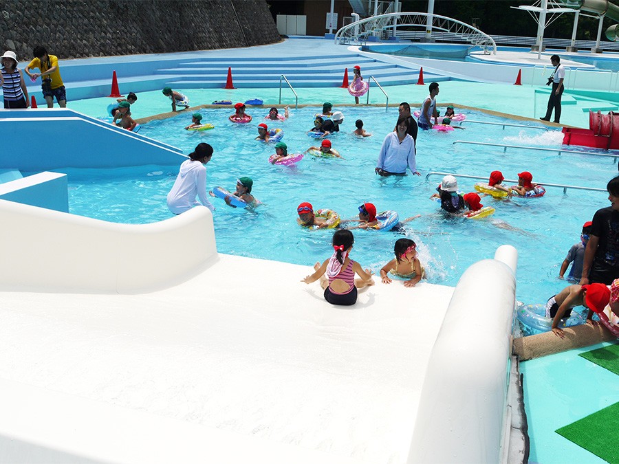 浅いプールで水遊びをする子どもたちとスタッフ