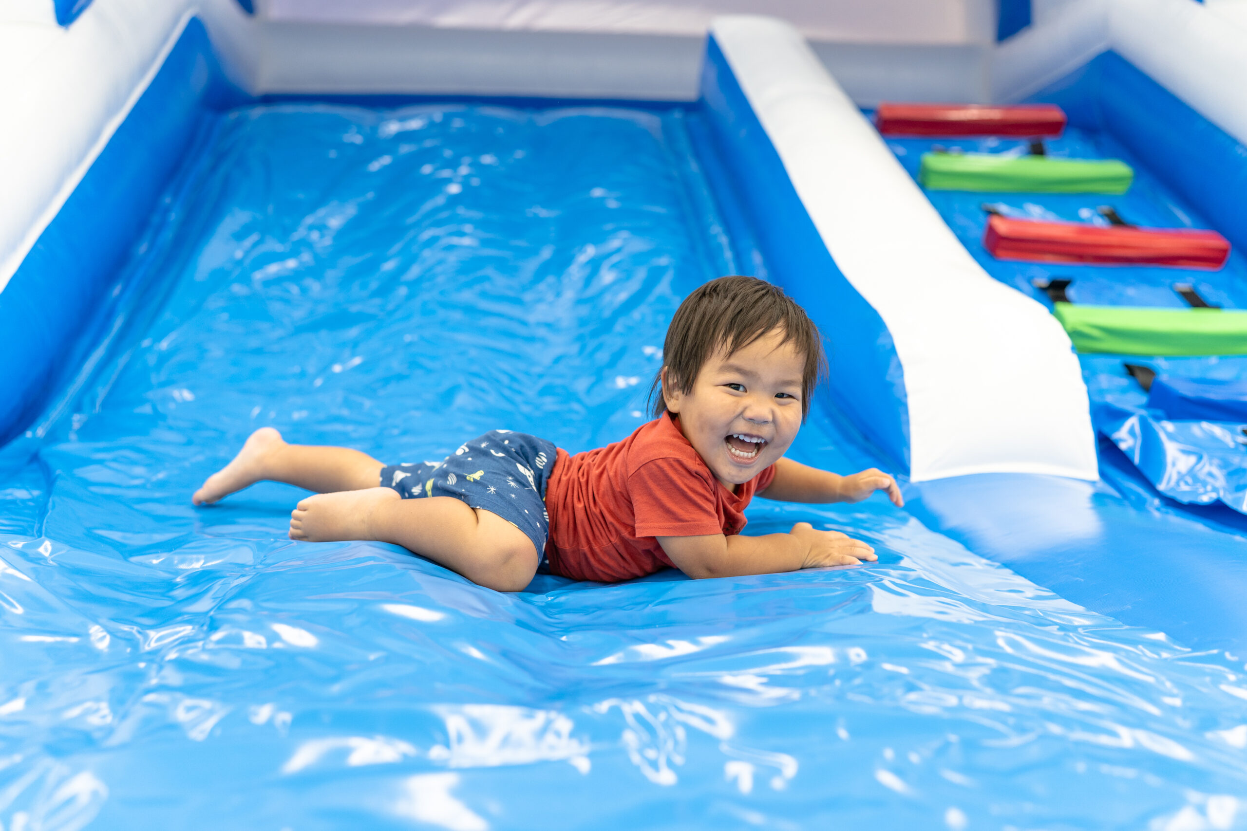 キッズランドUSの室内遊び場で滑り台を楽しむ男の子