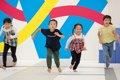 カラフルな壁の前を走る子どもたち