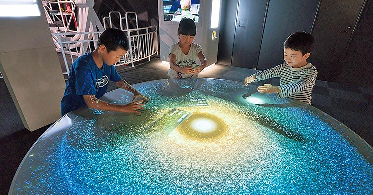 宇宙ゾーンの光るテーブルに手をかざす子どもたち(福岡市科学館)