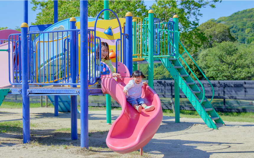 カラフルな複合遊具のすべり台をすべる子ども