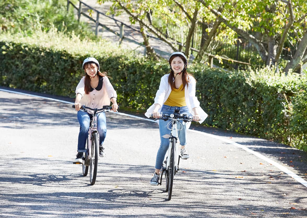 木立に囲まれたサイクリングコースを自転車で走る2人