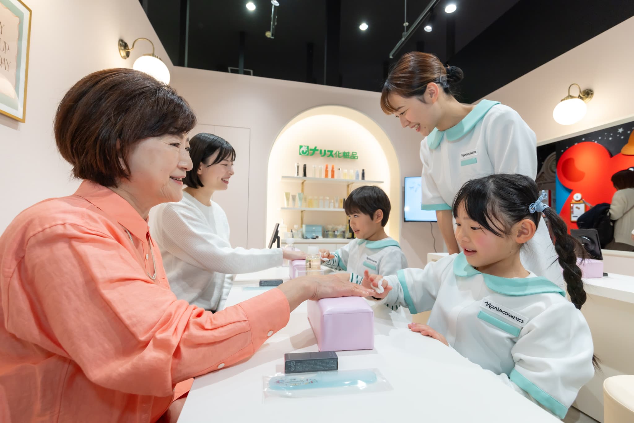 ナリス化粧品のエステティシャン体験で大人の手をお手入れする子ども