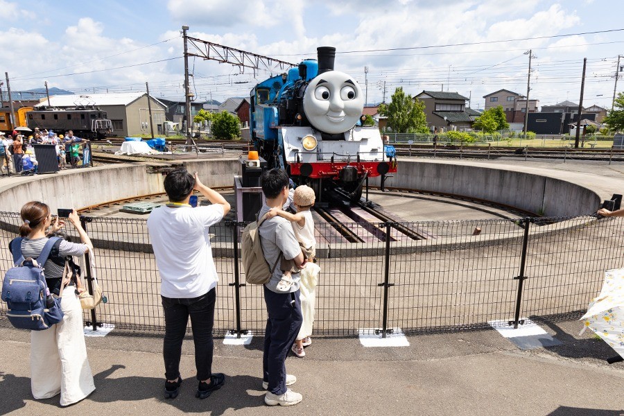 転車台の上のトーマス号を柵の外から見る家族連れ