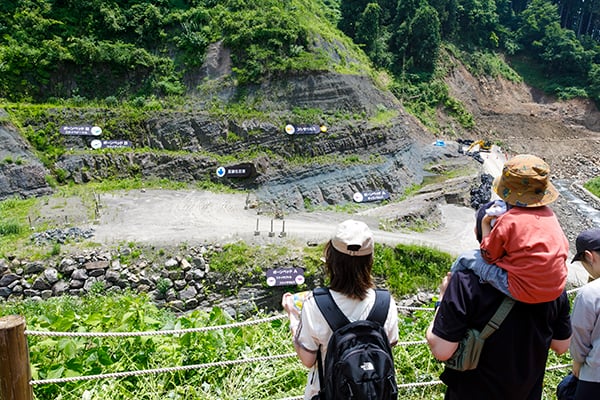 観察広場から見下ろす恐竜化石の発掘現場と見学する親子