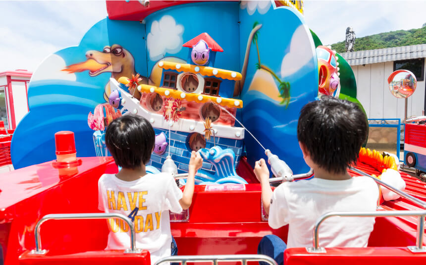 消防車型の遊具で放水して的をねらう子ども2人