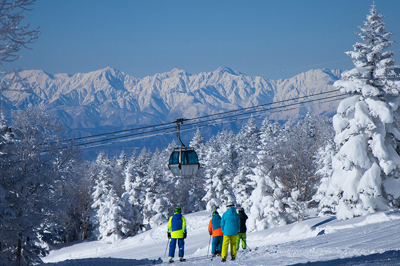 ゴンドラの下を滑るスキーヤーと雪山