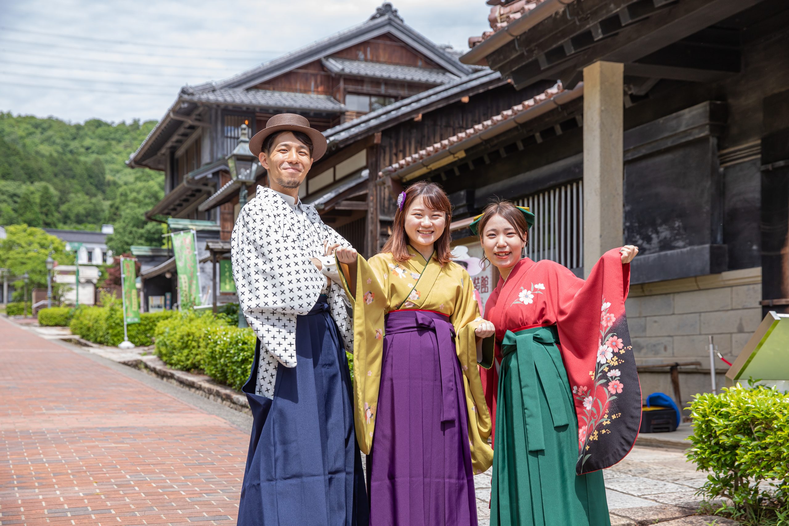 女学生の袴と書生服を着てレンガ通りに立つ3人
