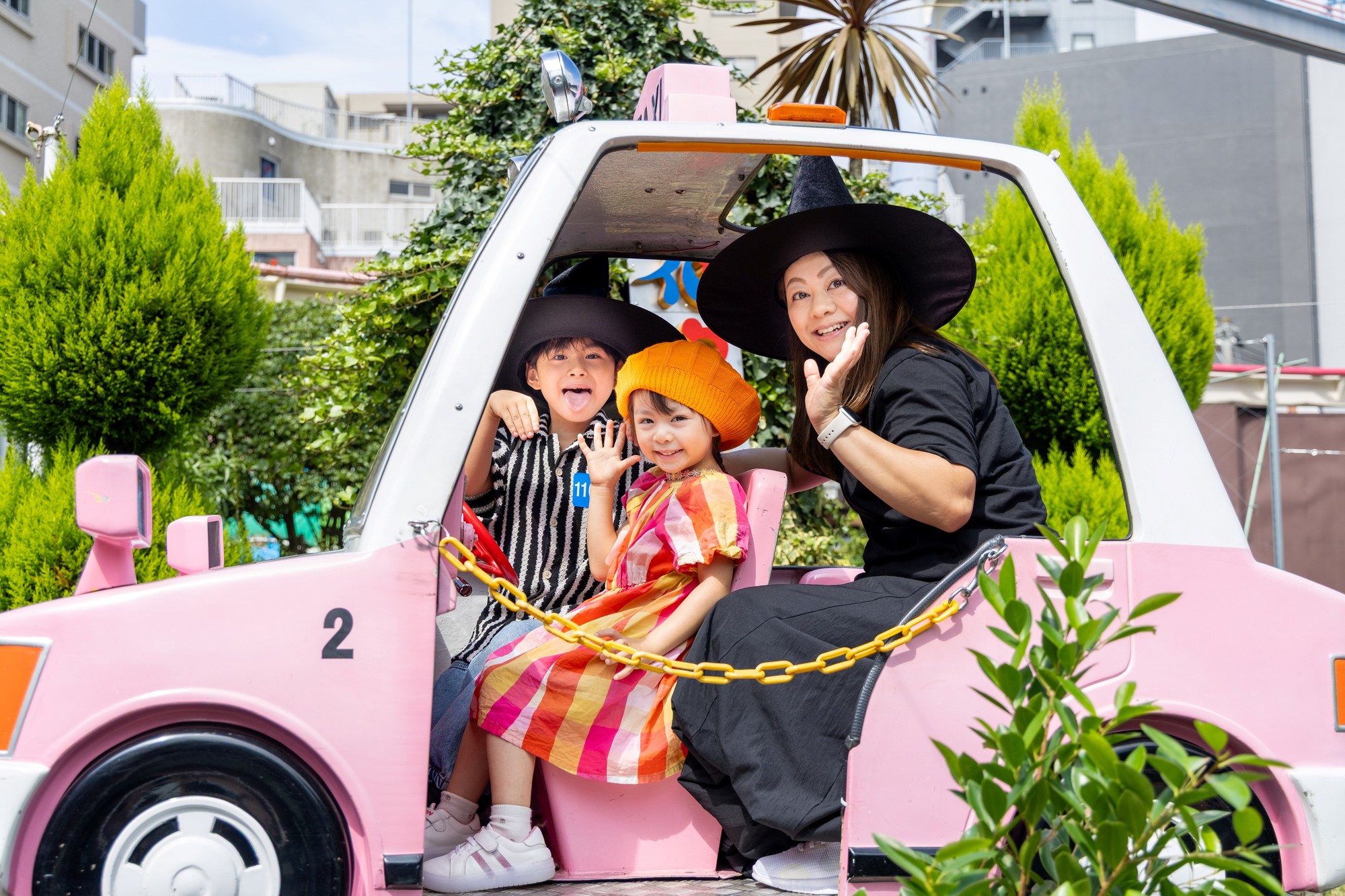 魔女の帽子をかぶってちびっ子タクシーに乗る親子