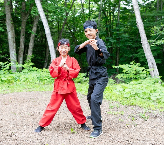 赤と黒の忍者服を着てポーズをとる子ども2人