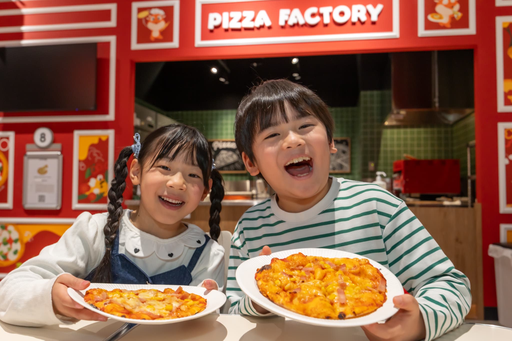 PIZZA FACTORYで焼き上げたピザを持つ2人の子ども
