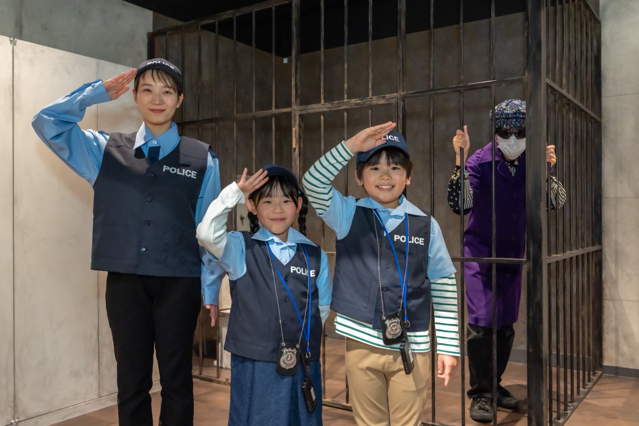 警察官の制服で敬礼する子どもたち