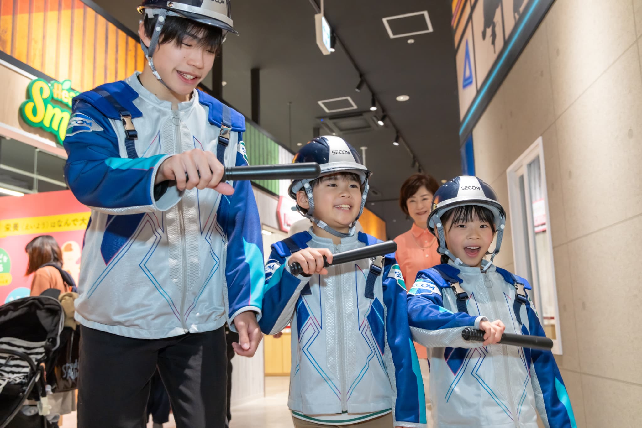 セコムの制服とヘルメットで館内を巡回する子どもたち