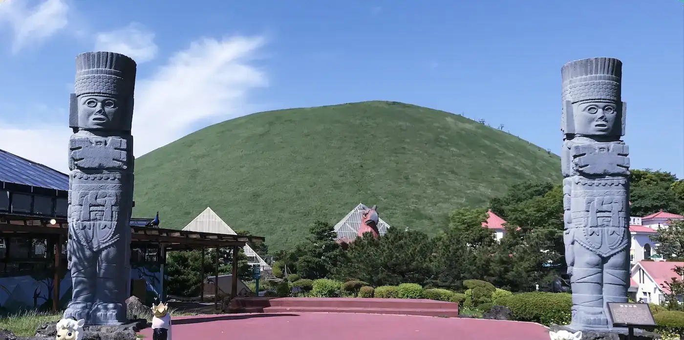 伊豆シャボテン動物公園 太陽の広場の石像と背景の大室山