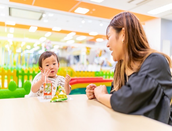 飲食休憩コーナーのテーブル席で飲み物を飲む子ども