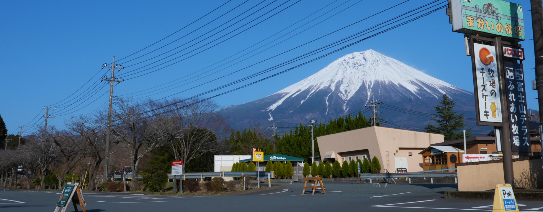 まかいの牧場の看板と駐車場の奥に見える富士山