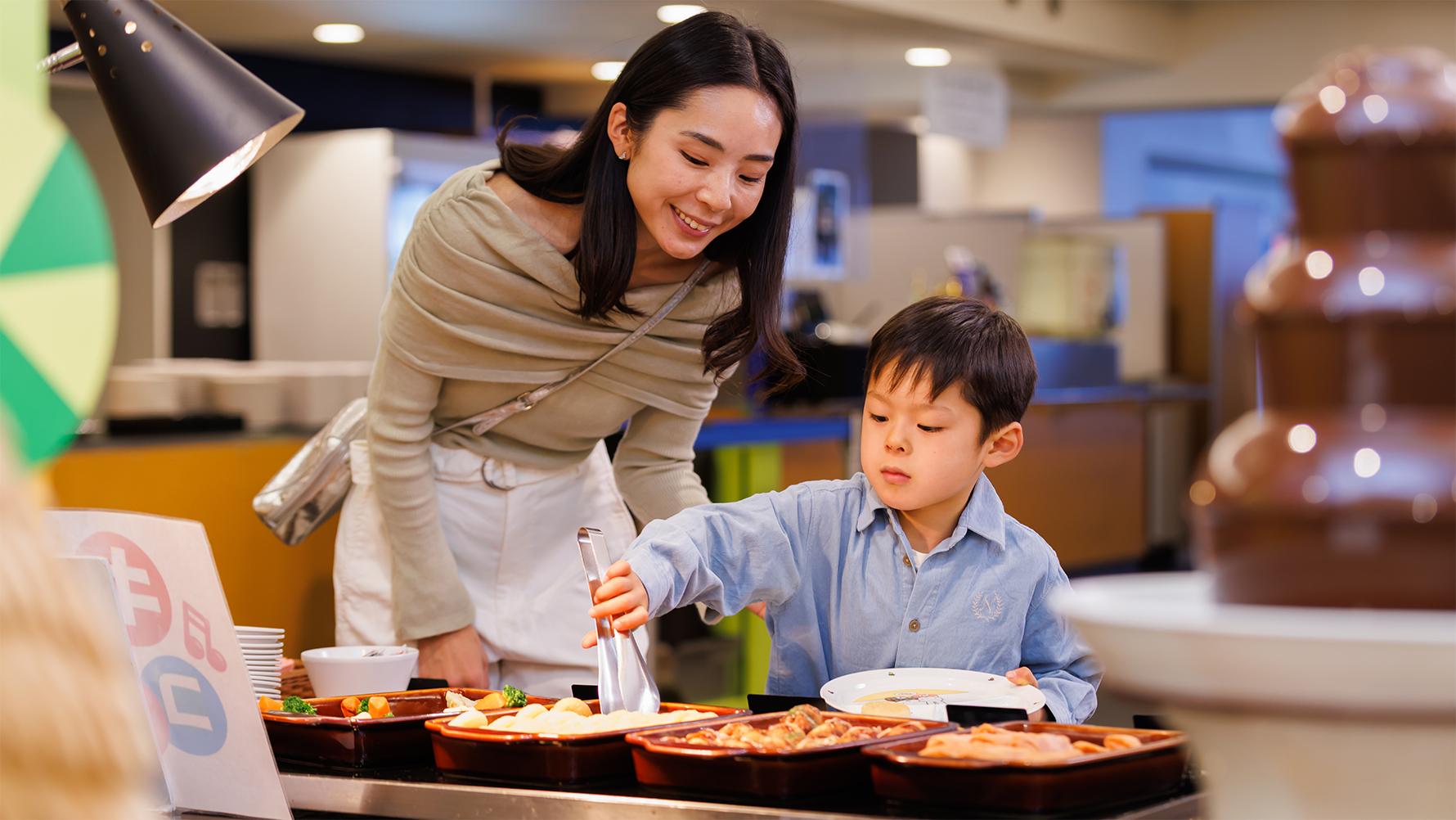ブッフェ台で料理を取る男の子と母親