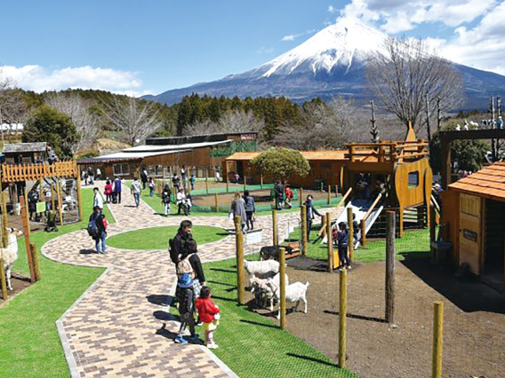 富士山を背にした動物の柵が並ぶ園内の小道