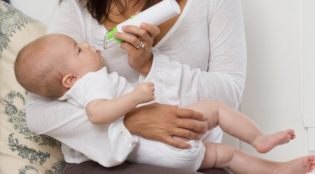 ハンディ型の鼻水吸引器で抱っこした赤ちゃんの鼻水を吸う人