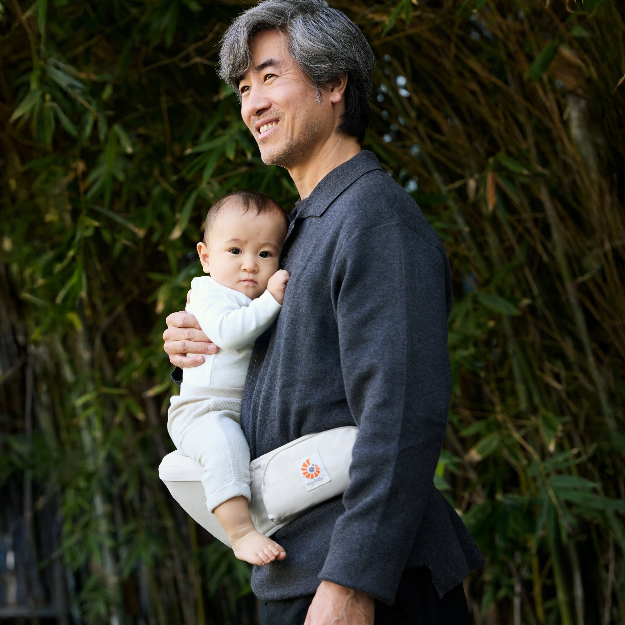 ヒップシートに赤ちゃんを座らせて抱っこする男性