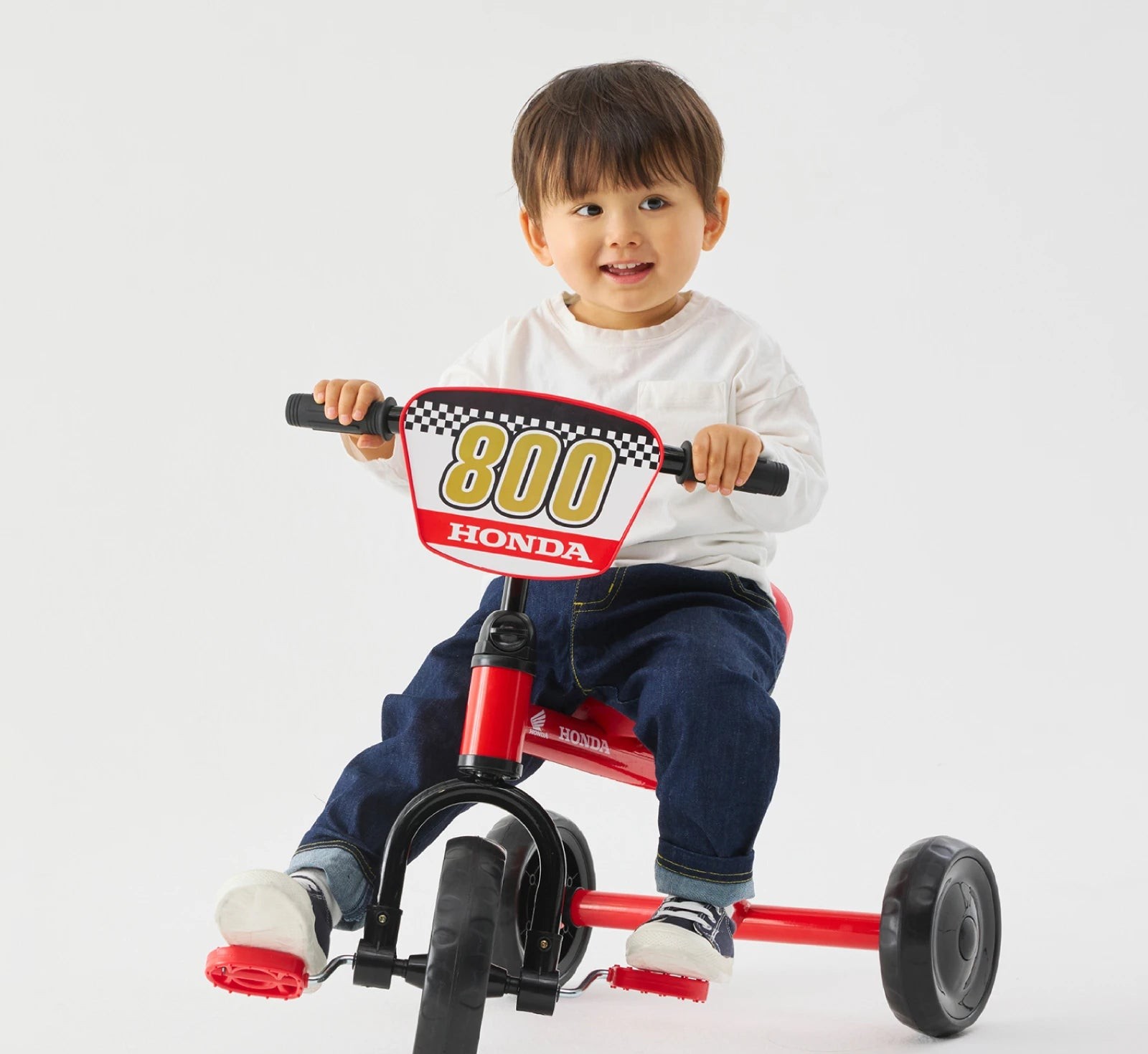 赤い三輪車に乗って笑う男の子