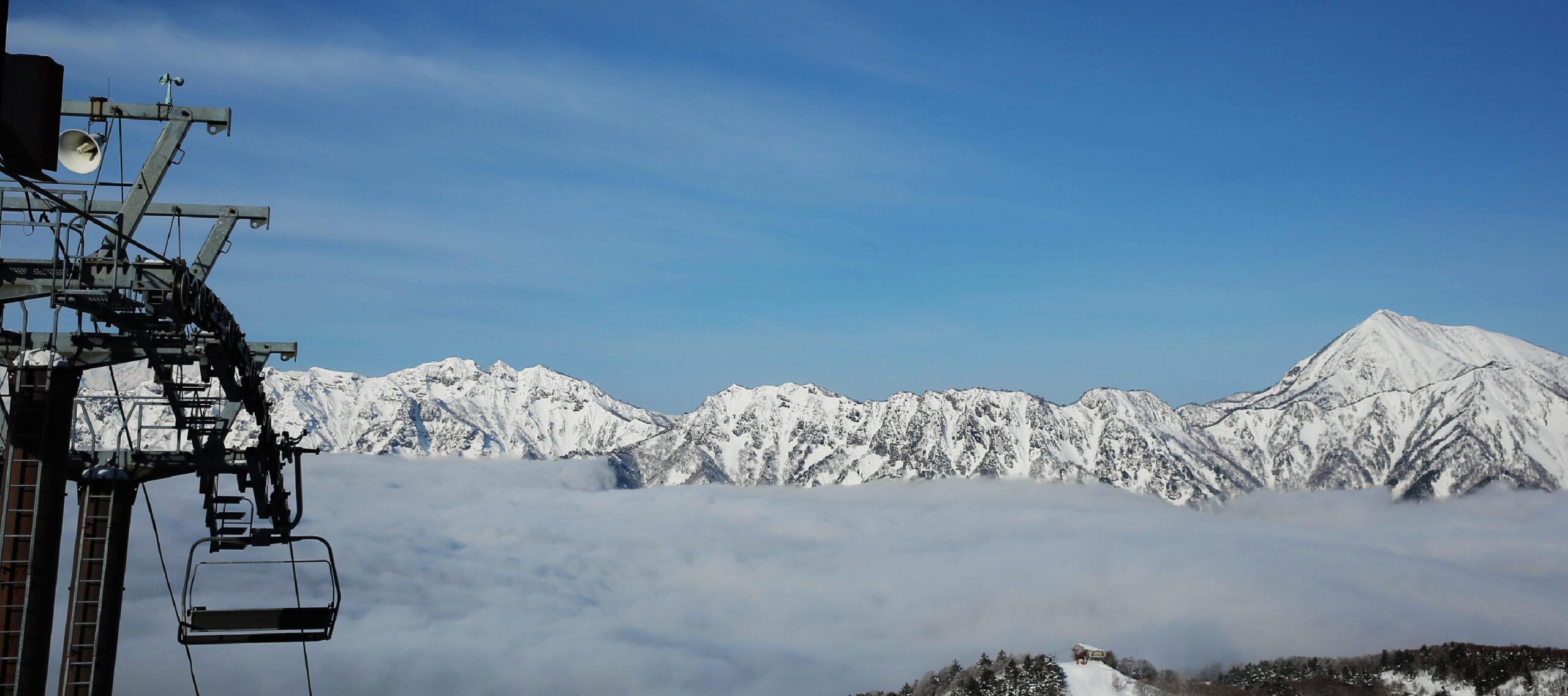 雲海の上に連なる雪山とリフト乗り場