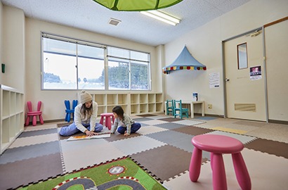 マットを敷いたキッズルームで遊ぶ親子
