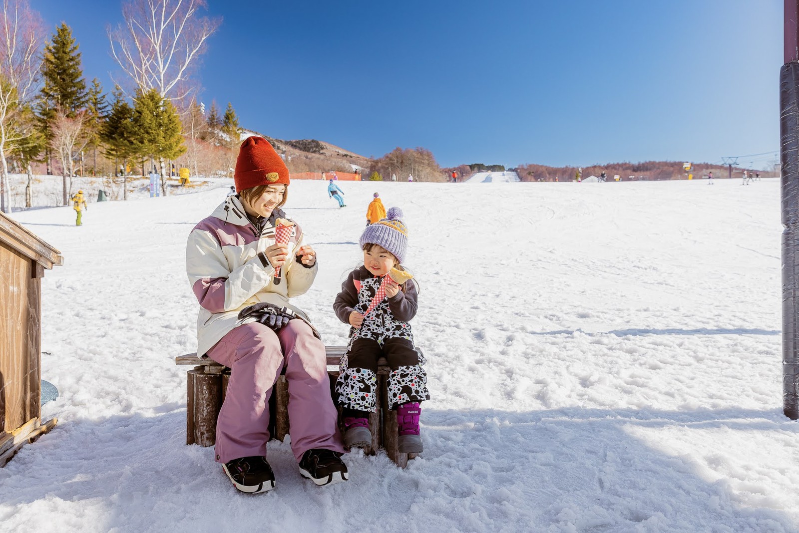 雪の上のベンチで休む親子