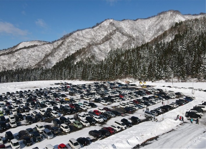 雪山のふもとに広がる駐車場の空撮