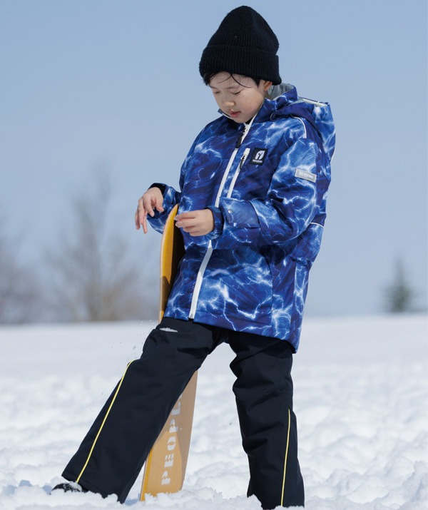 雪の上に立つジュニア用スキーウェアの子ども