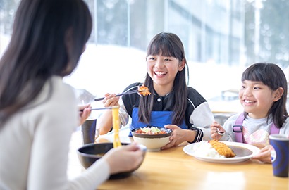 窓際の席で昼食をとる家族