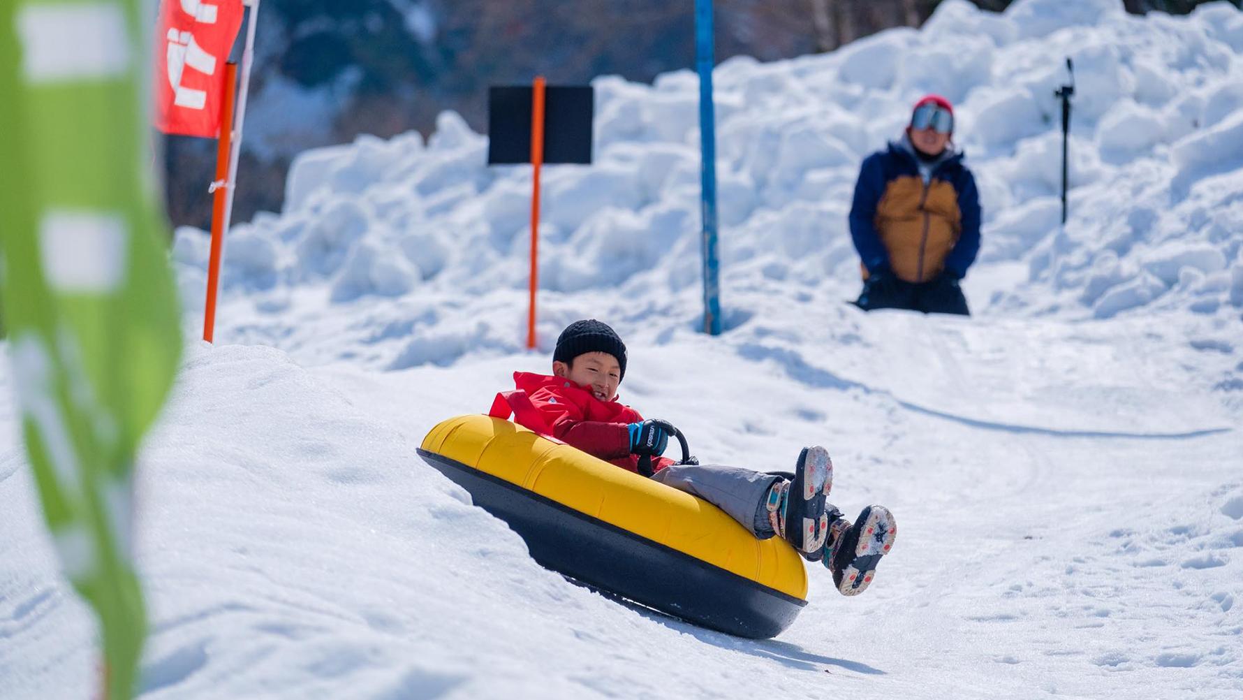 チュービングで雪の坂を滑る子ども