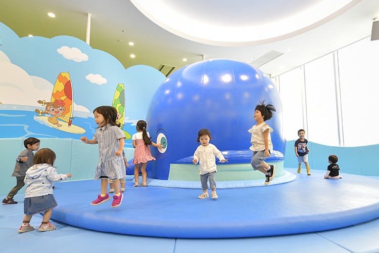 大きなクジラのまわりでジャンプする子どもたち