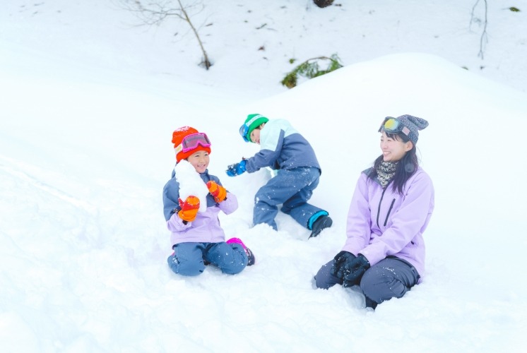 雪あそび広場で雪だるまを作る親子